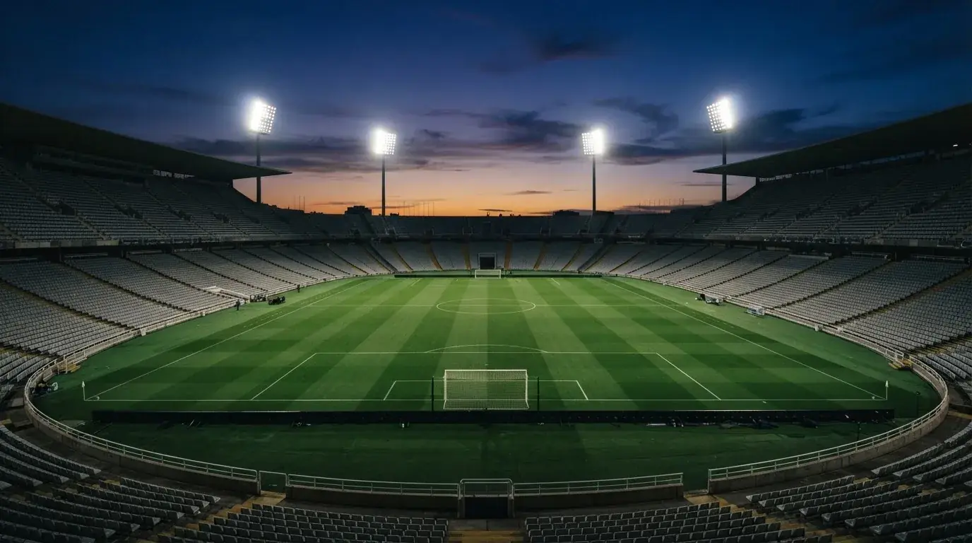 Een leeg voetbalstadion met lichtmasten bij schemering