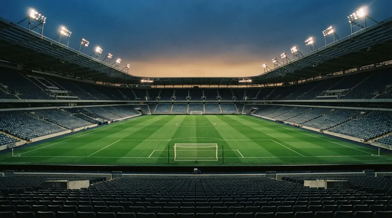 Een leeg voetbalstadion met lichtmasten bij schemering