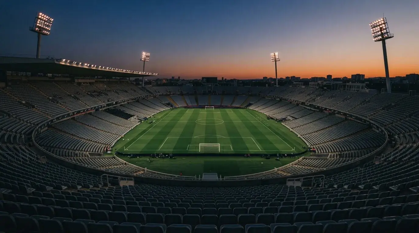 Een leeg voetbalstadion met lichtmasten bij schemering