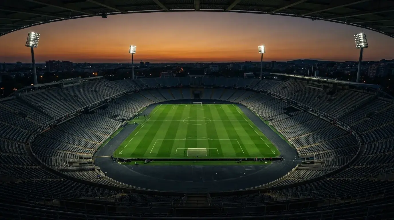 Een leeg voetbalstadion met lichtmasten bij schemering