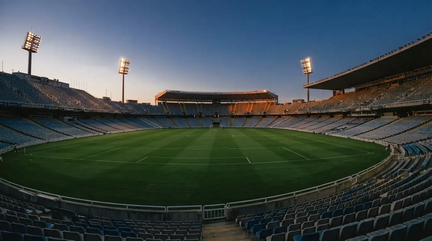 Een leeg voetbalstadion met lichtmasten bij schemering