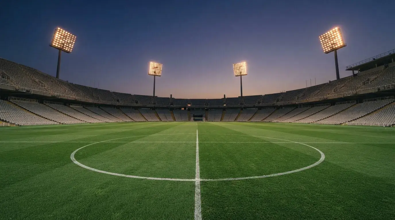 Een leeg voetbalstadion met lichtmasten bij schemering