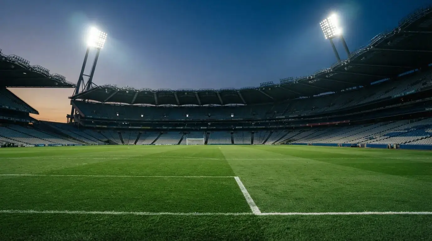 Een leeg voetbalstadion met lichtmasten bij schemering