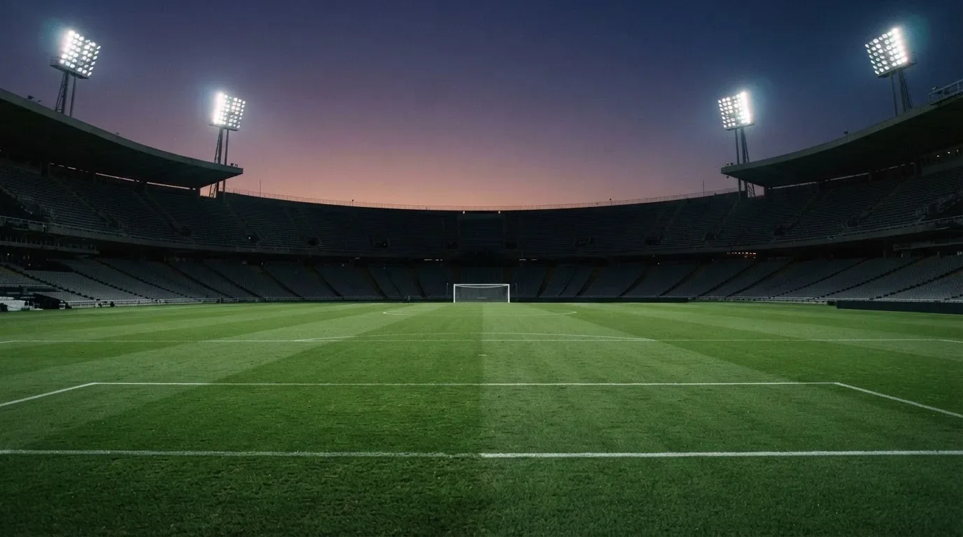 Een leeg voetbalstadion met lichtmasten bij schemering