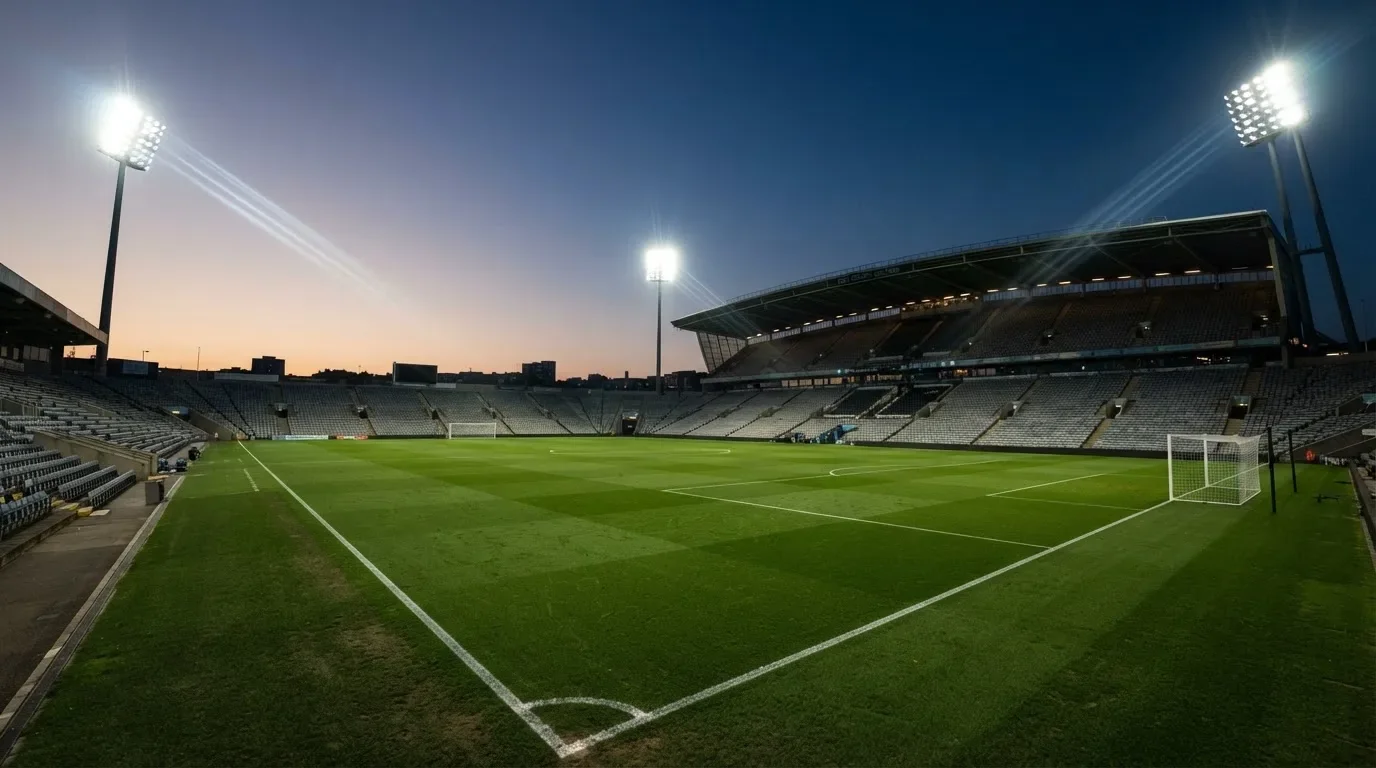 Een leeg voetbalstadion met lichtmasten bij schemering