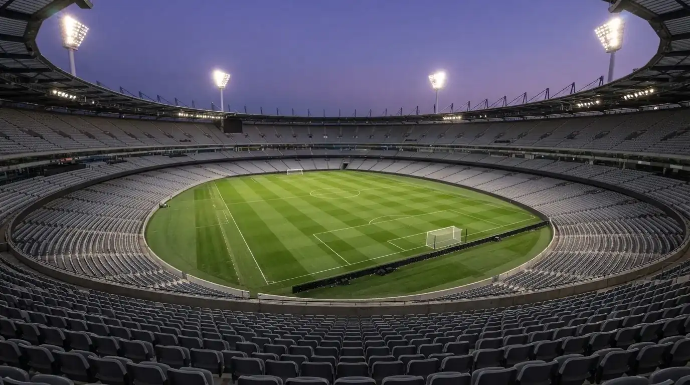 Een leeg voetbalstadion met lichtmasten bij schemering
