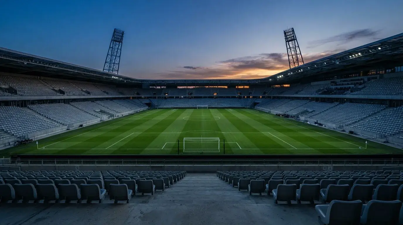 Een leeg voetbalstadion met lichtmasten bij schemering