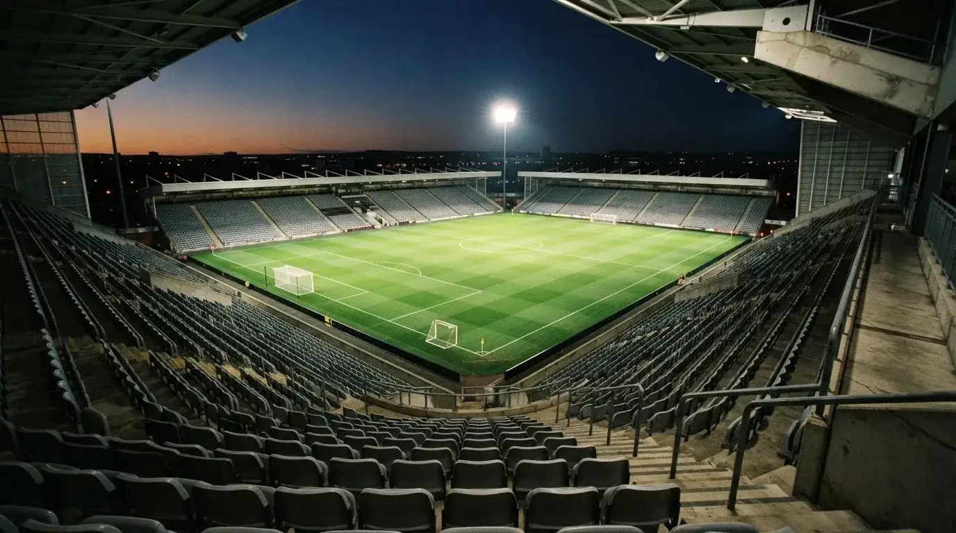 Een leeg voetbalstadion met lichtmasten bij schemering