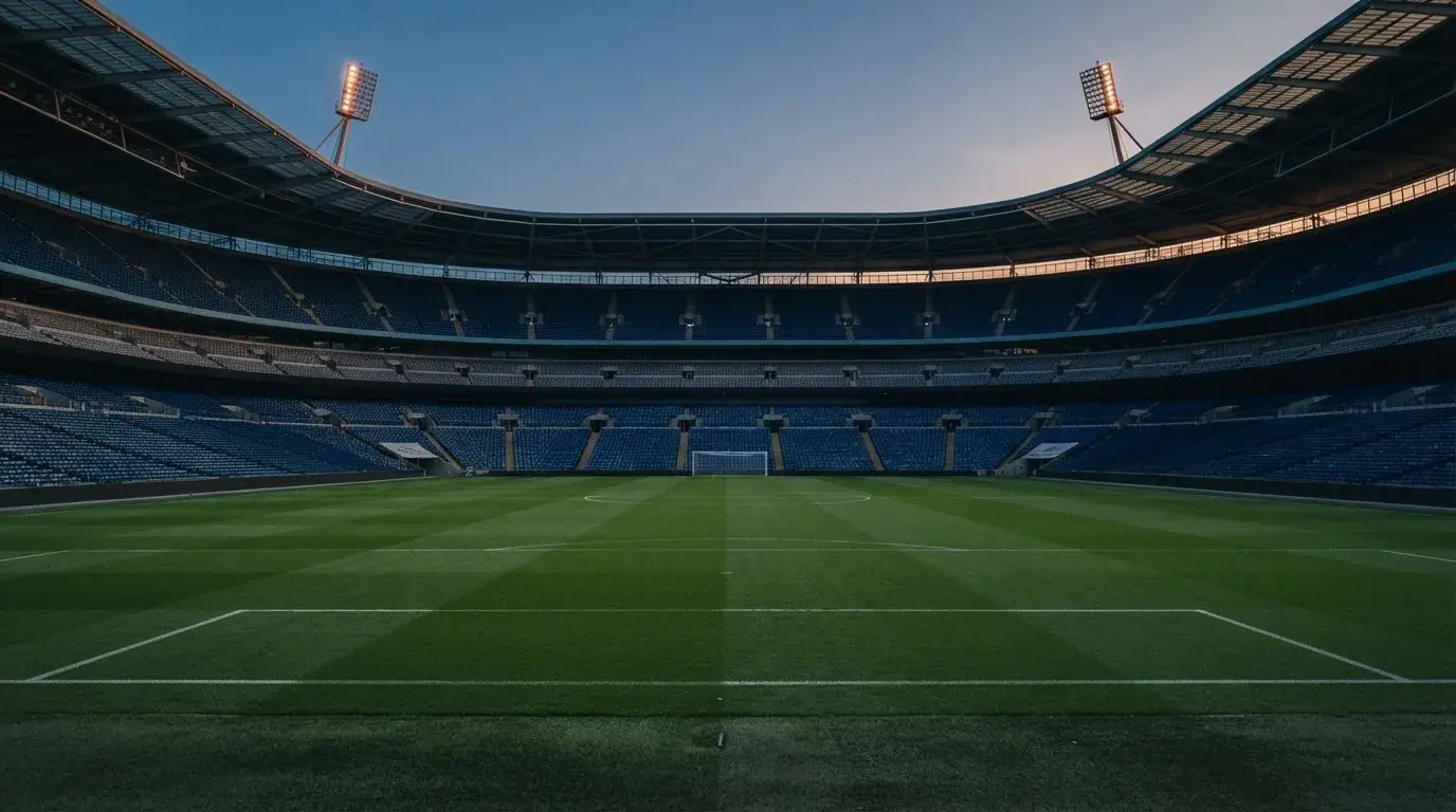 Een leeg voetbalstadion met lichtmasten bij schemering