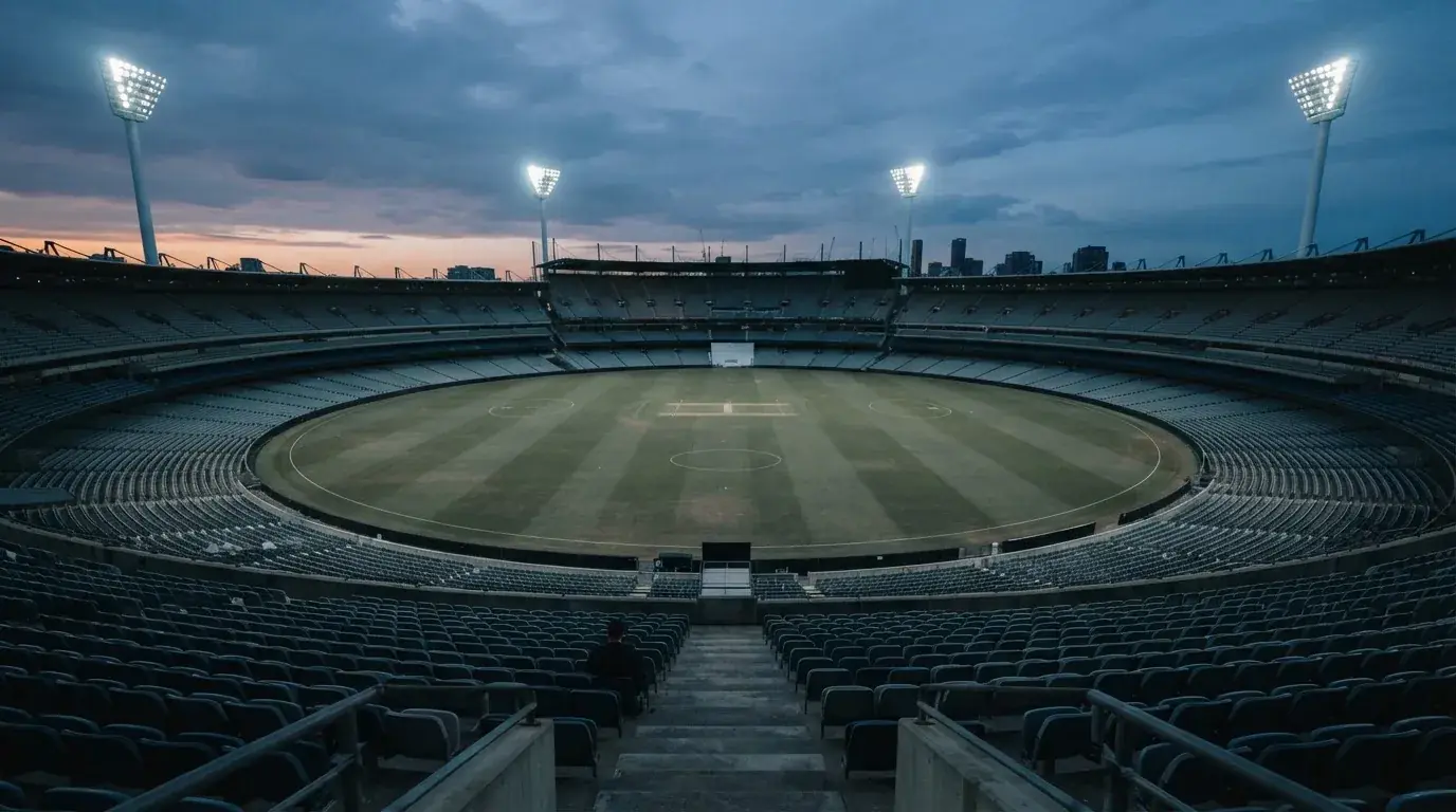 Een leeg voetbalstadion met lichtmasten bij schemering