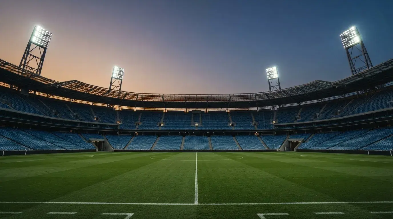 Een leeg voetbalstadion met lichtmasten bij schemering
